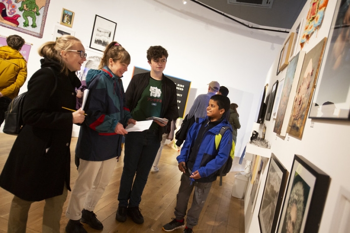 Four young people in a row, discussing art work on display on the wall in front of them