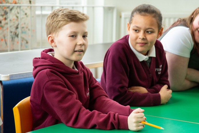 Male and female students sat in a desk in a classroom
